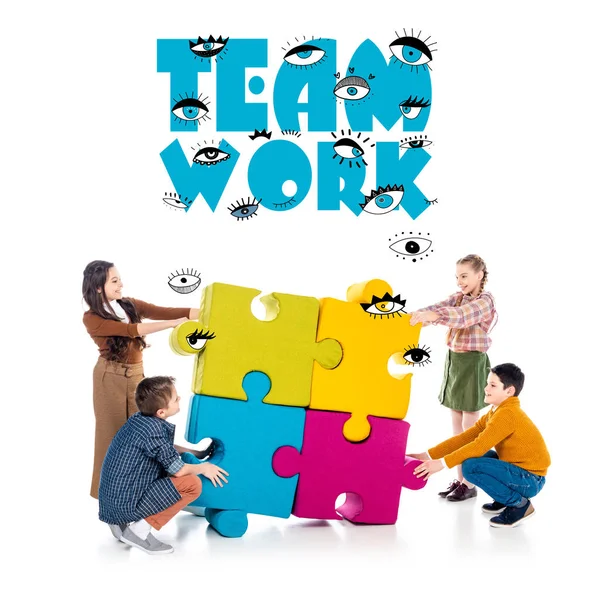 Bambini felici che giocano con pezzi di puzzle vicino al lavoro di squadra sul bianco — Foto stock