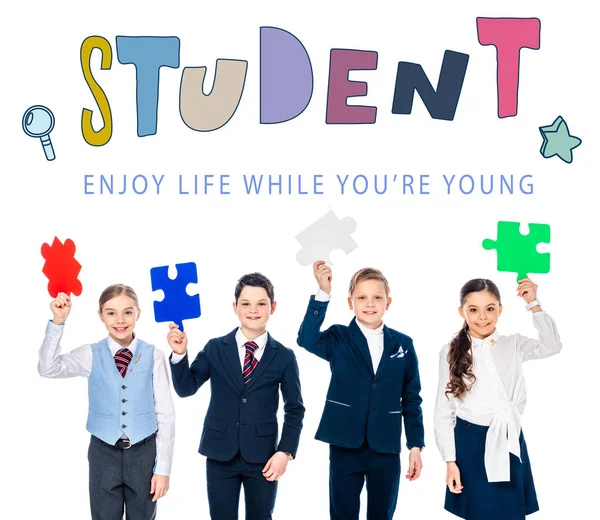 Happy kids in formal wear holding puzzle pieces near student letters on white — Stock Photo