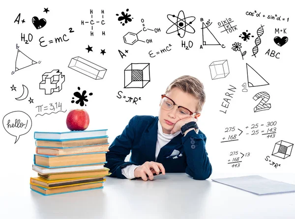 Triste colegial en gafas sentado en el escritorio con libros y manzana cerca de fórmulas matemáticas en blanco - foto de stock