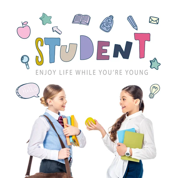 Schoolgirls in formal wear with books and apple near student letters on white — Stock Photo