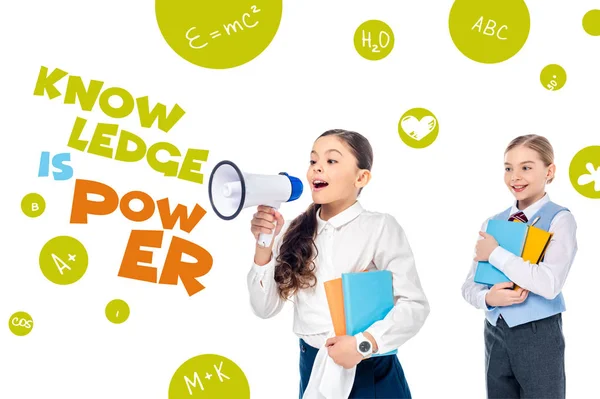 Schoolgirls in formal wear holding books and shouting in megaphone near knowledge is power letters on white — Stock Photo