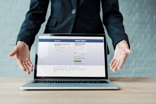 Kyiv, Ukraine - 5. August 2019: Ausgeschnittene Ansicht einer gestikulierenden Frau neben Laptop mit Facebook-Website auf dem Bildschirm — Stockfoto