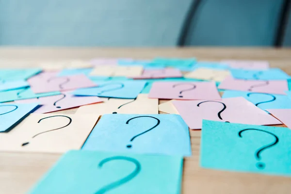 L'accent sélectif des points d'interrogation sur les notes collantes colorées sur la table — Photo de stock