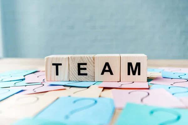 Selective focus of team lettering on cubes near sticky notes with question marks — Stock Photo