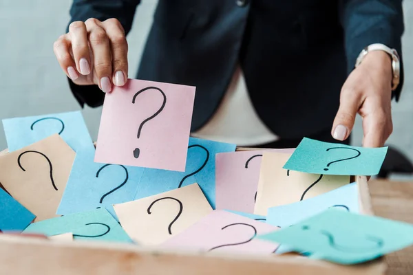 Cropped view of woman holding pink sticky note with question mark — Stock Photo