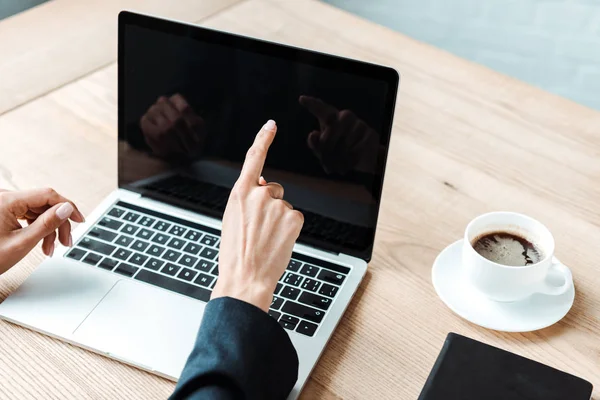 Cropped view of businesswoman pointing with finger at laptop with blank screen — Stock Photo