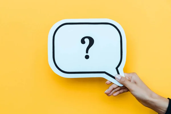 Cropped view of woman holding speech bubble with question mark on orange — Stock Photo