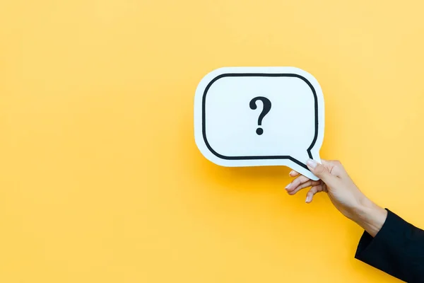 Cropped view of woman holding speech bubble with black question mark on orange — Stock Photo