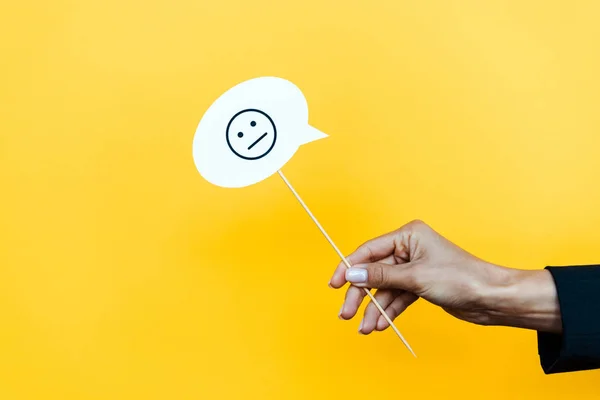 KYIV, UKRAINE - AUGUST 5, 2019: cropped view of woman holding stick with speech bubble with displeased face on orange — Stock Photo