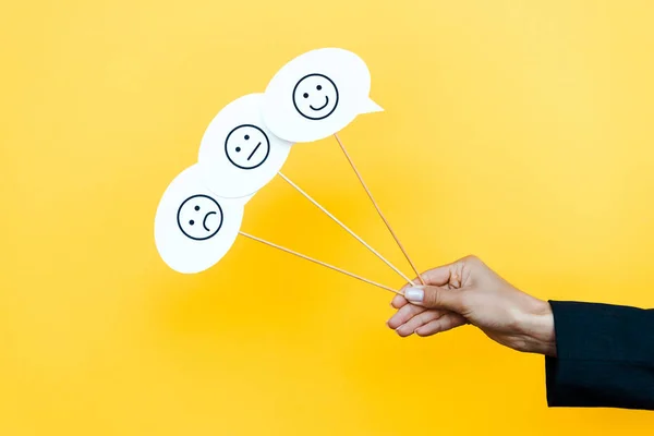 KYIV, UKRAINE - AUGUST 5, 2019: cropped view of woman holding set with emoticons on speech bubbles and sticks on orange — Stock Photo