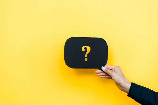 Cropped view of woman holding black speech bubble with question mark on orange — Stock Photo