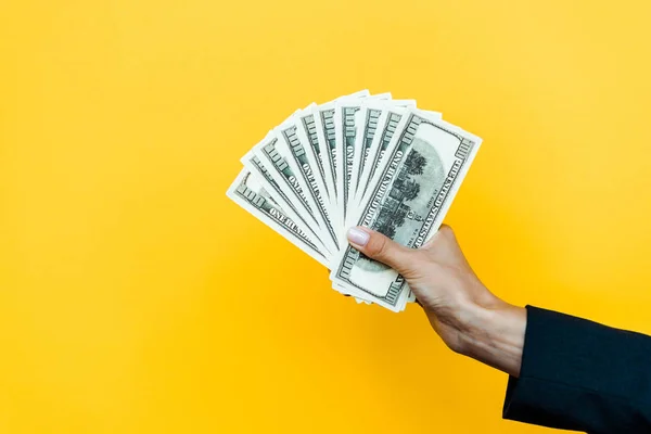 Cropped view of woman holding dollar banknotes on orange — Stock Photo