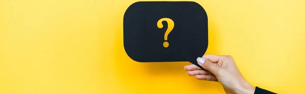 Panoramic shot of woman holding black speech bubble with question mark on orange — Stock Photo