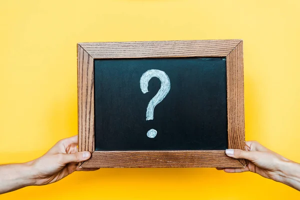 Cropped view of man and woman holding chalk board with question mark on orange — Stock Photo