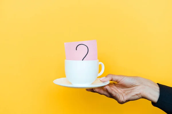 Vista recortada de la mujer sosteniendo platillo blanco y taza aislada en naranja - foto de stock