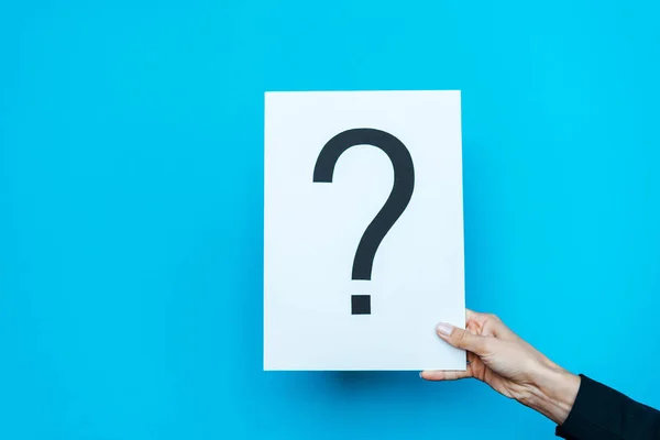 Cropped view of woman holding board with placard with question mark on blue — Stock Photo