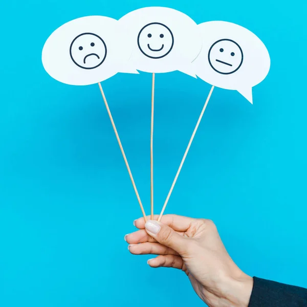 KYIV, UKRAINE - AUGUST 5, 2019: cropped view of woman holding set with emoticons on speech bubbles on blue — Stock Photo