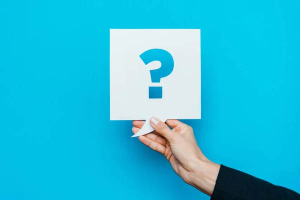 Cropped view of woman holding speech bubble with question mark on blue — Stock Photo