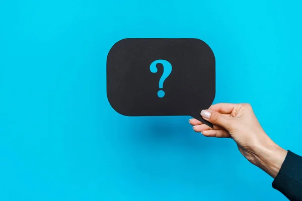 Cropped view of woman holding black speech bubble with question mark on blue — Stock Photo