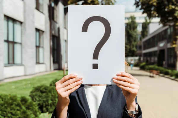 Cropped view of woman holding placard with question mark near building outside — Stock Photo