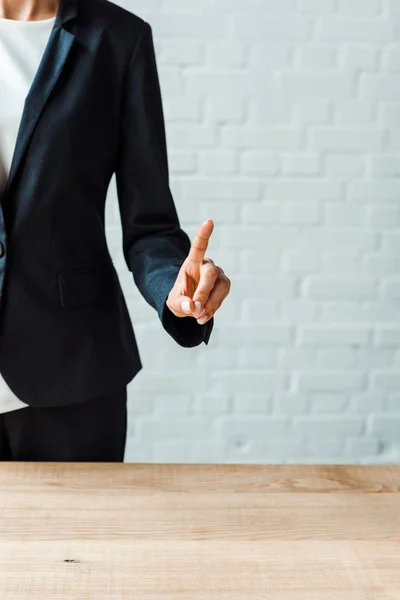 Cropped view of businesswoman in formal wear pointing with finger in office — Stock Photo