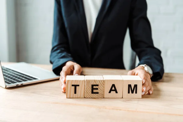 Selektiver Fokus einer Geschäftsfrau, die Holzwürfel mit Teambuchstaben berührt — Stockfoto