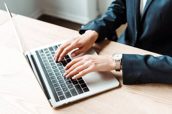 Vue recadrée de la femme tapant sur ordinateur portable tout en travaillant dans le bureau — Photo de stock