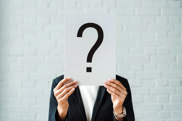 Cropped view of woman holding placard with question mark near brick wall — Stock Photo