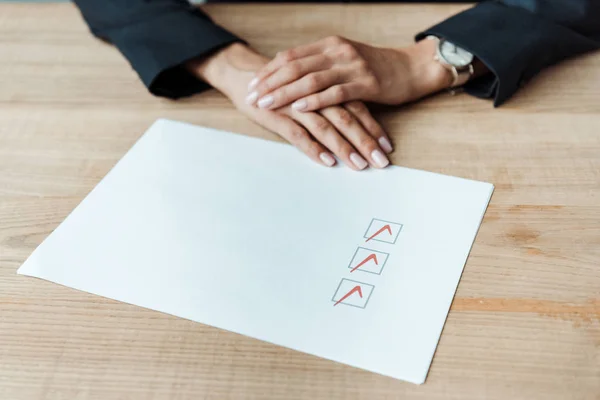 Cropped view of businesswoman with clenched hands near check list — Stock Photo