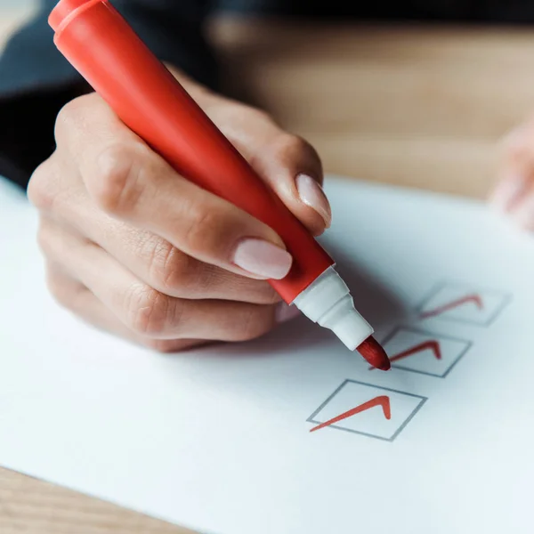 Close up of woman putting check park in check list — Stock Photo