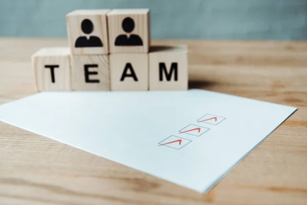 Selective focus of check list near wooden cubes with team letters — Stock Photo