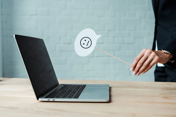 KYIV, UKRAINE - AUGUST 5, 2019: cropped view of woman holding stick with displeased  face near laptop — Stock Photo