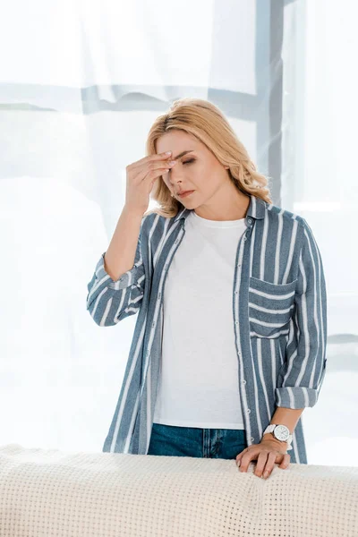 Blonde woman touching head while having headache at home — Stock Photo