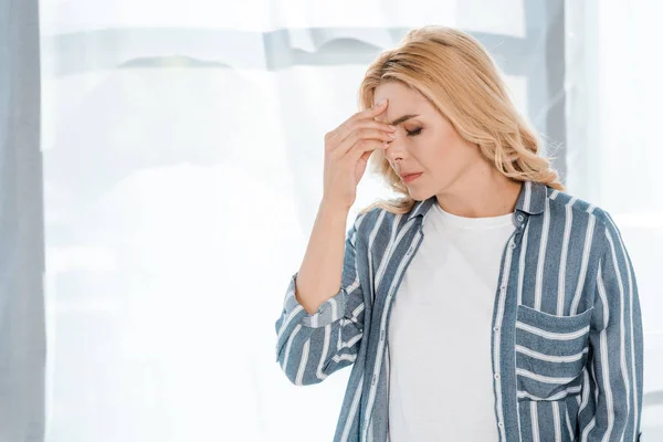 Mujer emocional tocando la cabeza mientras tiene dolor de cabeza en casa - foto de stock