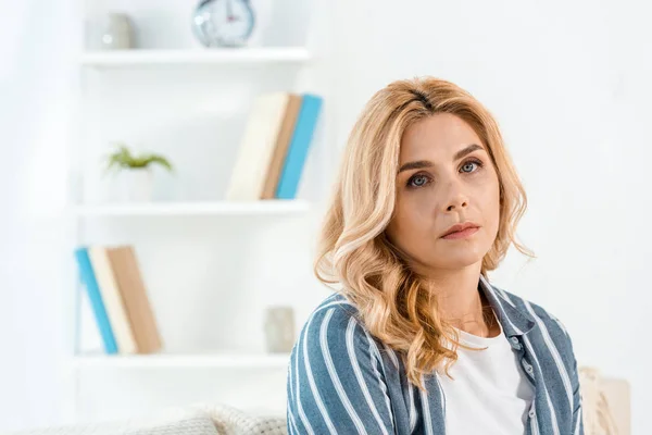 Traurige Frau mit schlechter Laune blickt im Wohnzimmer in die Kamera — Stockfoto