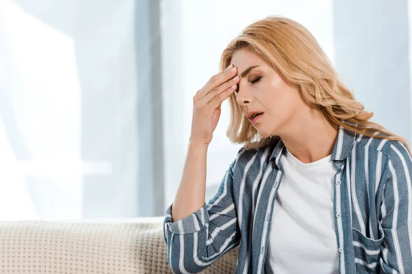 Upset woman with closed eyes touching head at home — Stock Photo