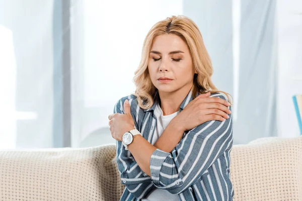 Woman with closed eyes touching shoulders at home — Stock Photo