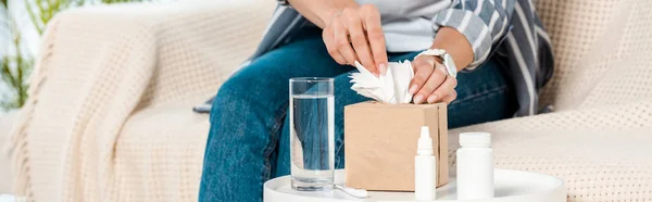 Tiro panorámico de la mujer tocando la servilleta cerca del vaso de agua - foto de stock