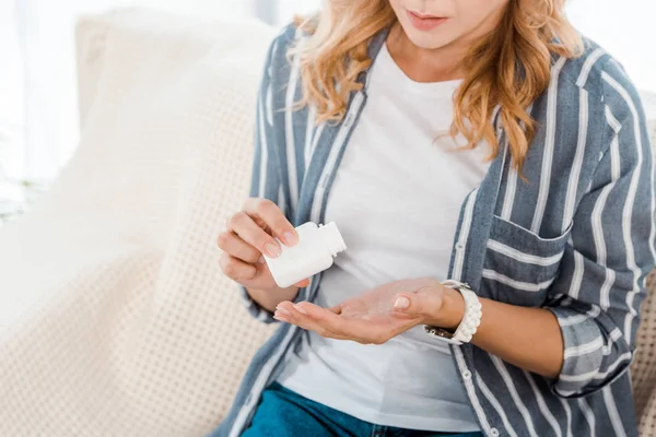 Cropped view of woman with cupped hand holding bottle with pills — Stock Photo