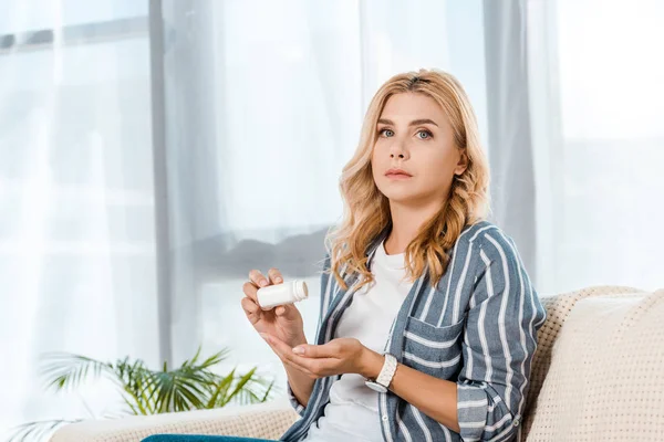 Sick woman with cupped hand holding bottle with pills — Stock Photo