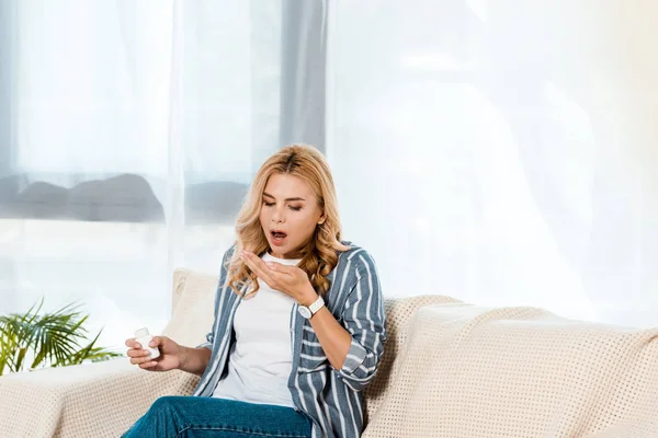 Donna sorpresa guardando mano mentre tiene in mano bottiglia con pillole — Foto stock