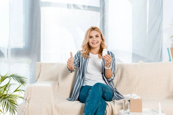 Mujer feliz mostrando el pulgar hacia arriba y sosteniendo la botella con pastillas - foto de stock