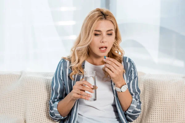 Woman taking pill while holding glass with water — Stock Photo