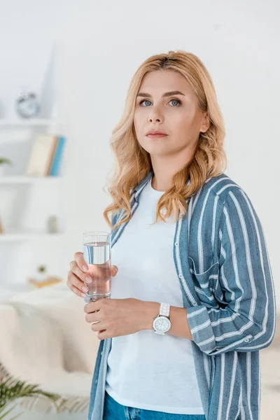 Frau blickt in Kamera, während sie Glas mit Wasser hält — Stockfoto