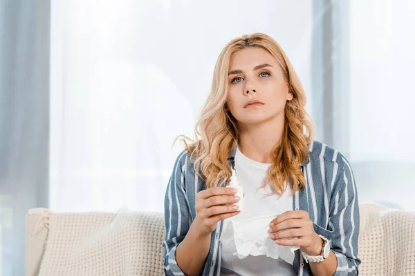 Sick woman holding nasal spray and napkin in living room — Stock Photo