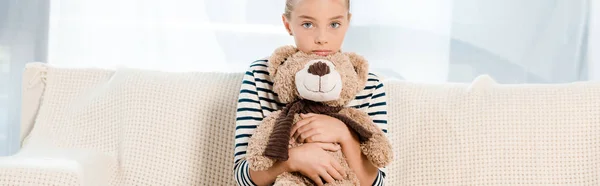 Panoramic shot of kid holding teddy bear in living room — Stock Photo