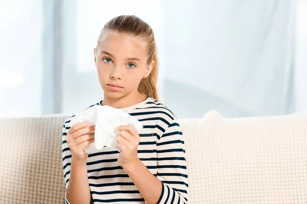 Diseased kid holding tissue and looking at camera — Stock Photo