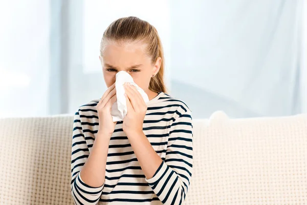 Diseased kid sneezing in tissue and looking at camera — Stock Photo