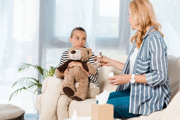 Filha segurando ursinho e olhando para a mãe — Fotografia de Stock