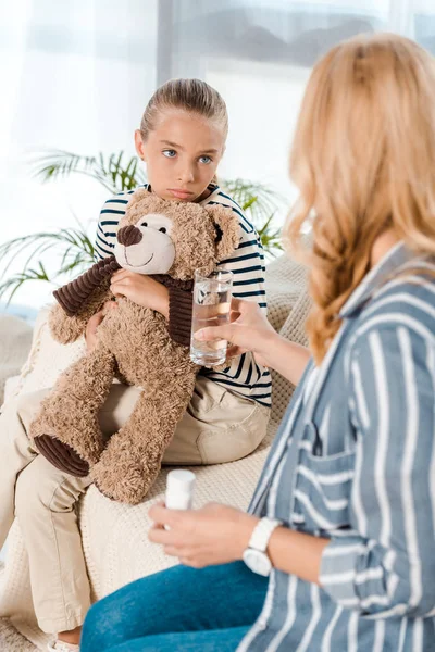 Selektiver Fokus der Tochter auf Mutter mit Flasche und Glas Wasser — Stockfoto